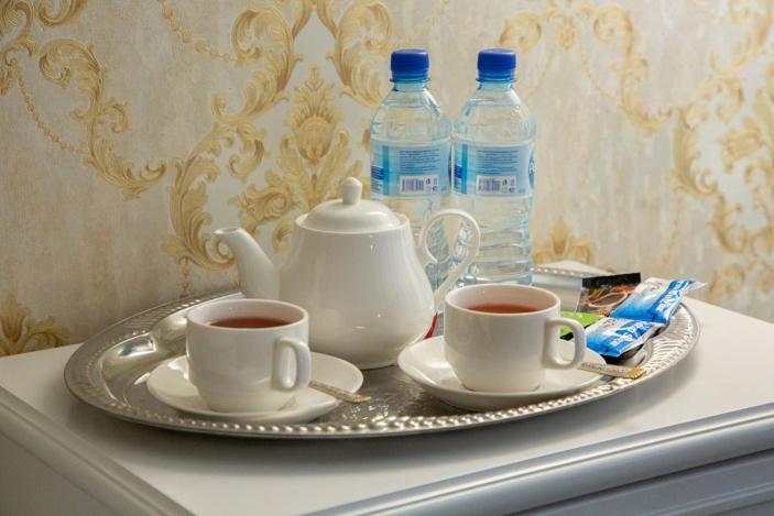 ORZU HOTEL في نمنغان: صينية مع كوبين من الشاي وزجاجتين من الماء