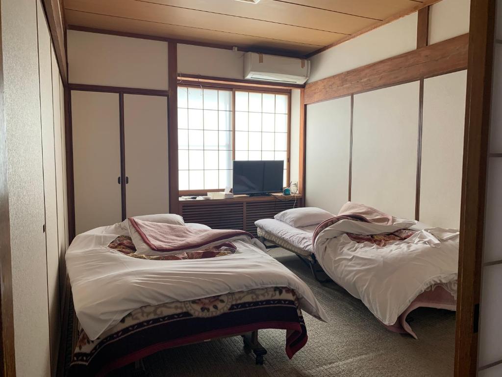 Cette chambre comprend 2 lits et une télévision. dans l'établissement 民宿ニュー万福茶屋, à Taketa