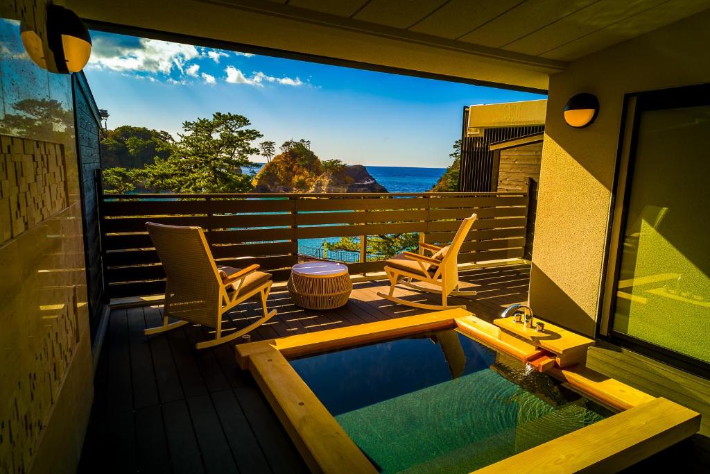 a balcony with a pool and chairs and the ocean at Mayu Futahari in Nishiizu