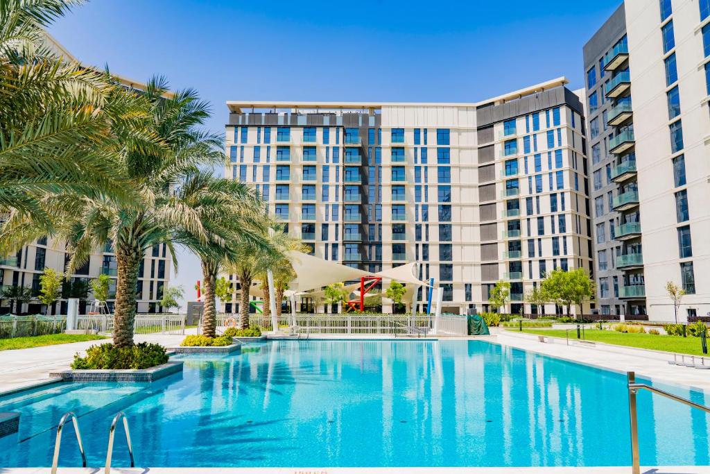 a swimming pool with palm trees in front of a building at Expo Village Serviced Apartments in Dubai