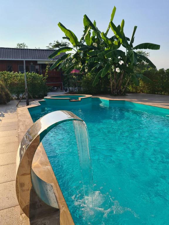 a swimming pool with a water fountain in the middle at Lampang Hideaway Guesthouse in Lampang