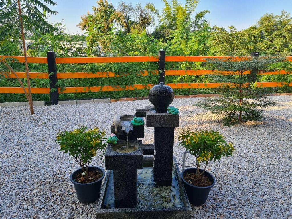 a fountain with two potted plants in front of a fence at Lampang Hideaway Guesthouse in Lampang