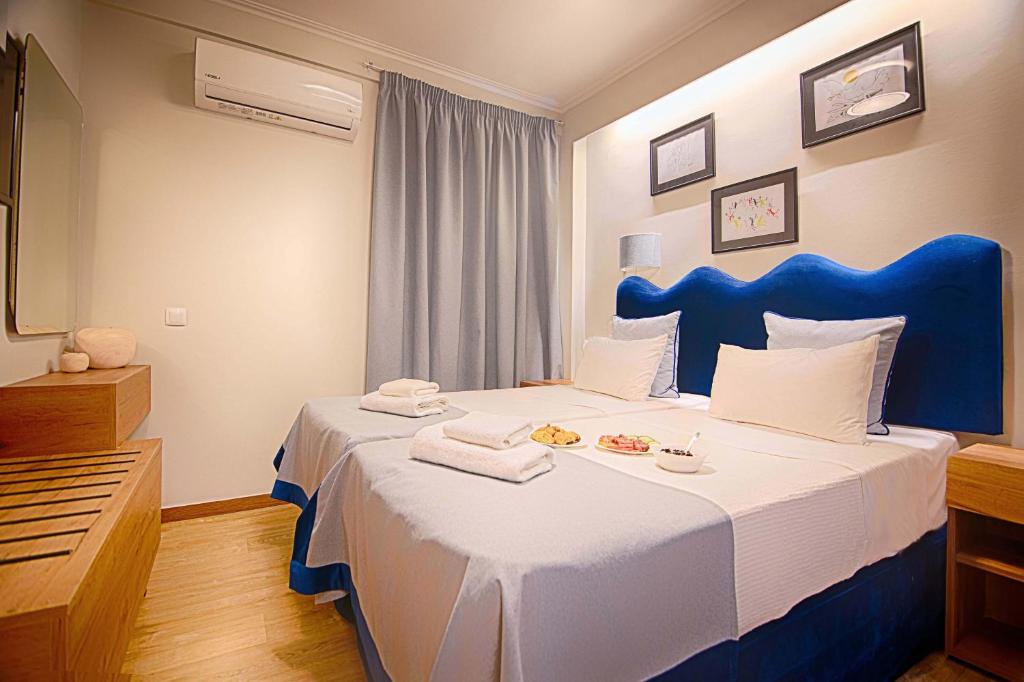 Schlafzimmer mit einem großen Bett mit blauem Kopfteil in der Unterkunft FALIREON HOTEL in Athen