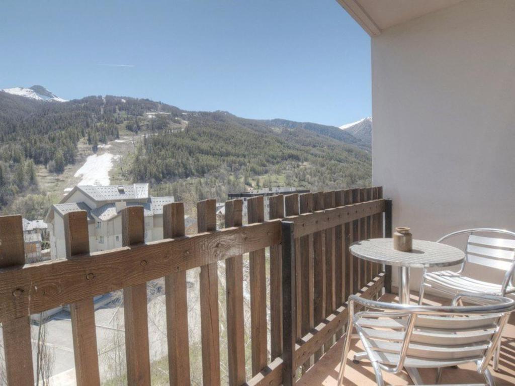 d'un balcon avec une table, des chaises et des montagnes. dans l'établissement Appartement cabine 6 pers avec balcons, proche pistes - Serre-Chevalier, Chantemerle - FR-1-330E-28, à Saint-Chaffrey