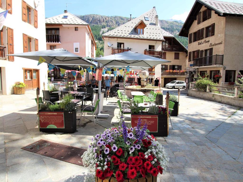 a patio with tables and umbrellas and flowers on a street at Appartement Le Monêtier-les-Bains, 2 pièces, 6 personnes - FR-1-330F-35 in Le Monêtier-les-Bains