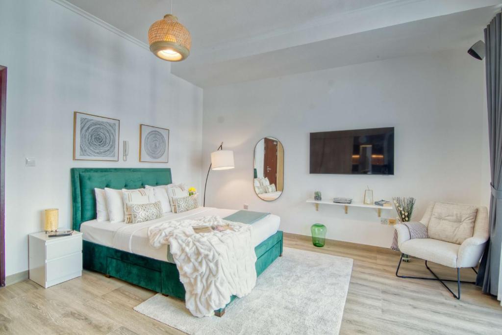 ein weißes Schlafzimmer mit einem Bett und einem Stuhl in der Unterkunft The Smart Concierge - DEC Tower in Dubai