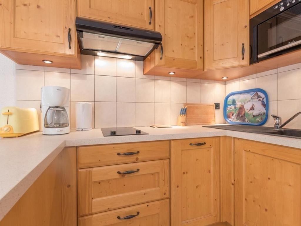 une cuisine avec des armoires en bois et un comptoir dans l'établissement Appartement 6 pers. à Chantemerle, Serre-Chevalier - Balcon, Parking, 2 étoiles - FR-1-330E-34, à Saint-Chaffrey