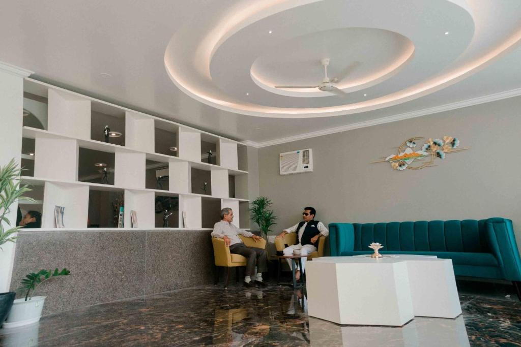 two people sitting in chairs in a waiting room at Hotel Grand Lotus in Dimāpur