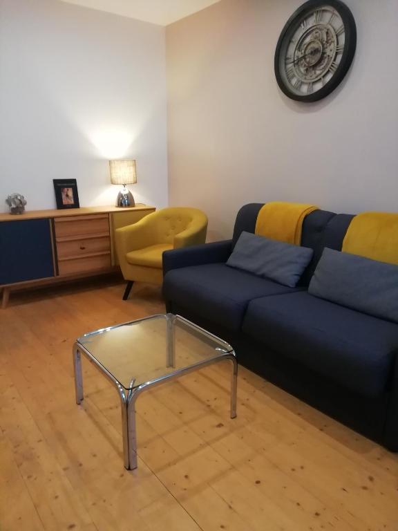 a living room with a blue couch and a glass coffee table at Jolie maison à 200 m des plages du débarquement in Saint-Aubin-sur-Mer