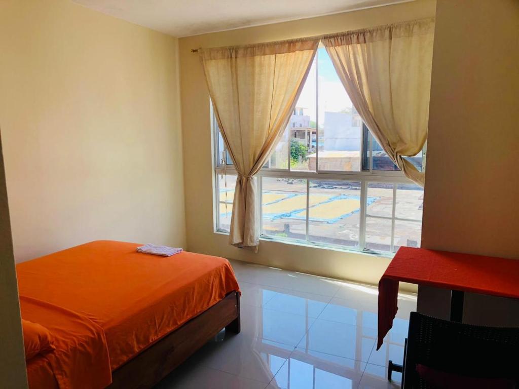 een slaapkamer met een bed en een groot raam bij Pelican House in Puerto Baquerizo Moreno