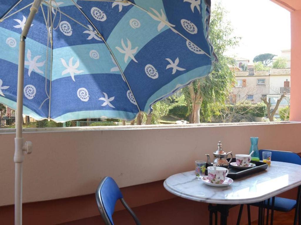 un tavolo con un ombrello blu in una finestra di Appartement Sainte-Maxime, 1 pièce, 4 personnes - FR-1-226-294 a Sainte-Maxime