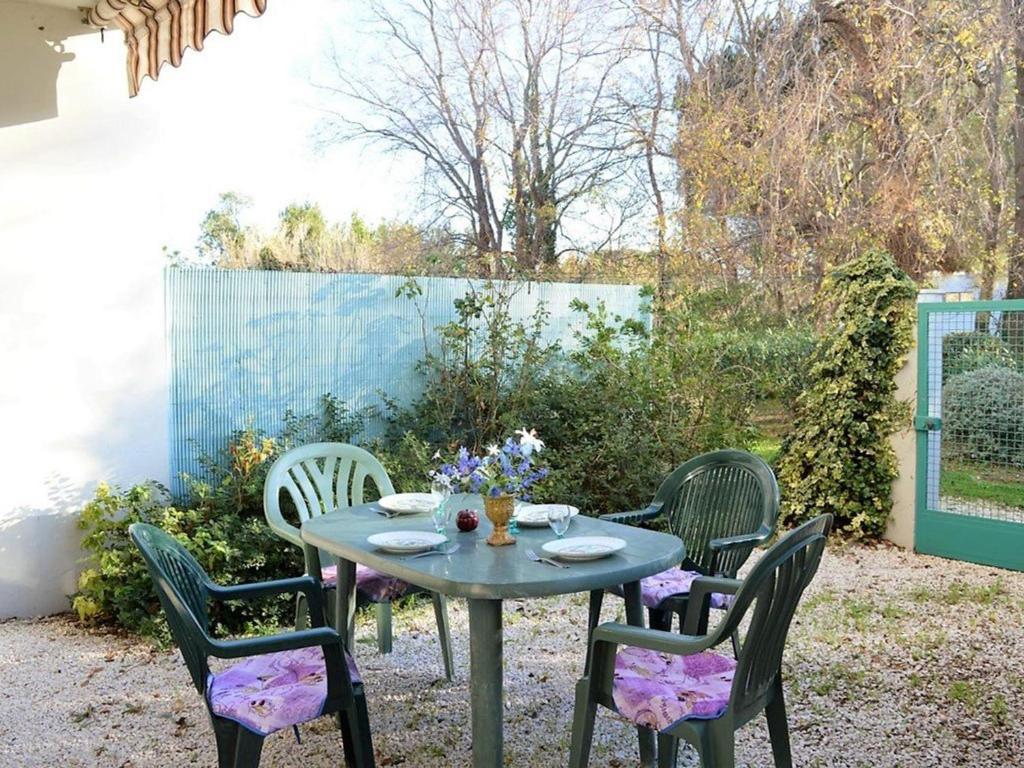 une table avec quatre chaises et une table avec des fleurs. dans l'établissement Studio climatisé au Lavandou avec terrasse, parking et environnement calme - 3 couchages - FR-1-251-167, au Lavandou