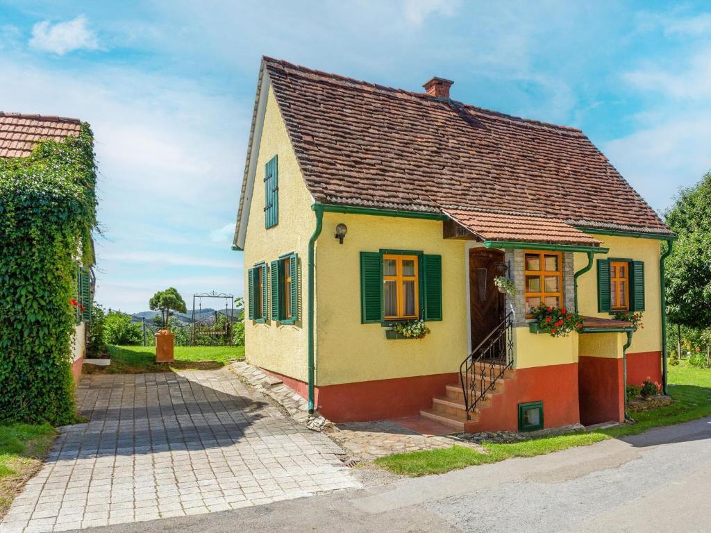 a small yellow and red house with green shutters at Holiday home in Gersdorf near a swimming lake in Gersdorf an der Feistritz