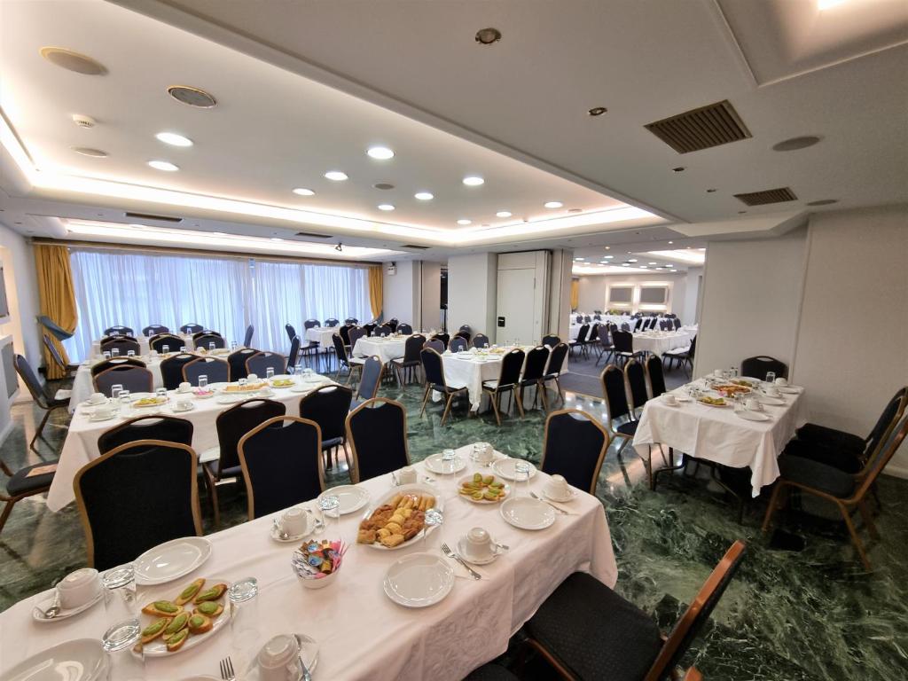 un salón de banquetes con mesas y sillas blancas en Savoy Hotel, en Pireo