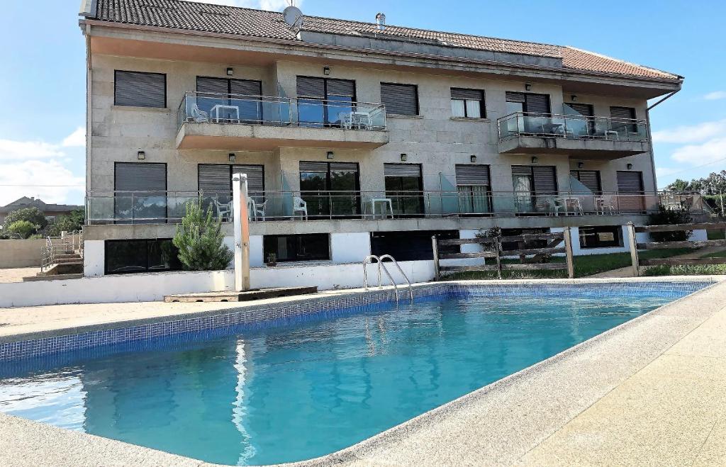 un edificio con piscina di fronte a un edificio di Apartamentos aDoniña Playa Major Sanxenxo a Sanxenxo