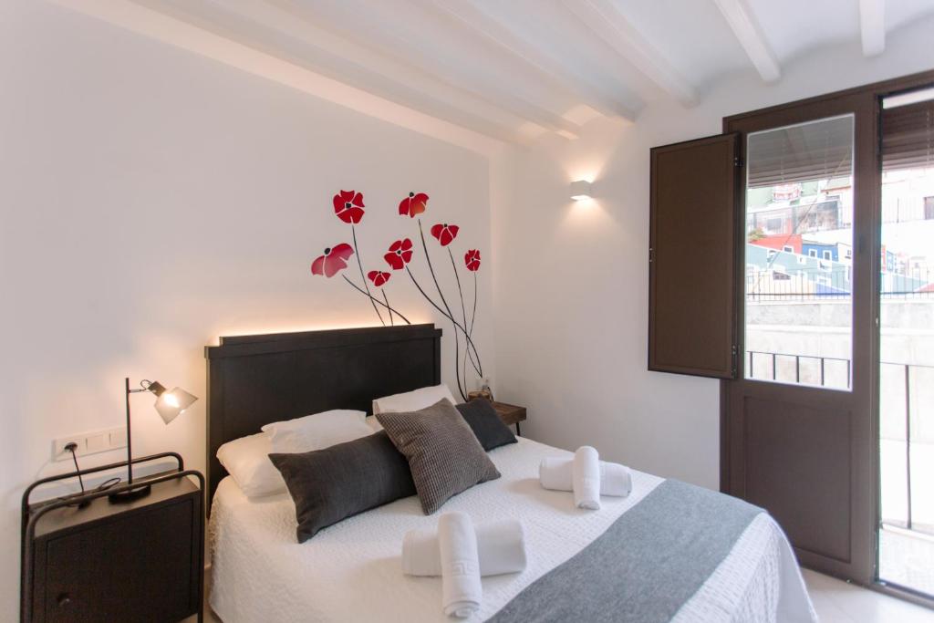 a bedroom with a bed and a vase with red flowers at VILASUITES Beach, Sand & Menta in Villajoyosa