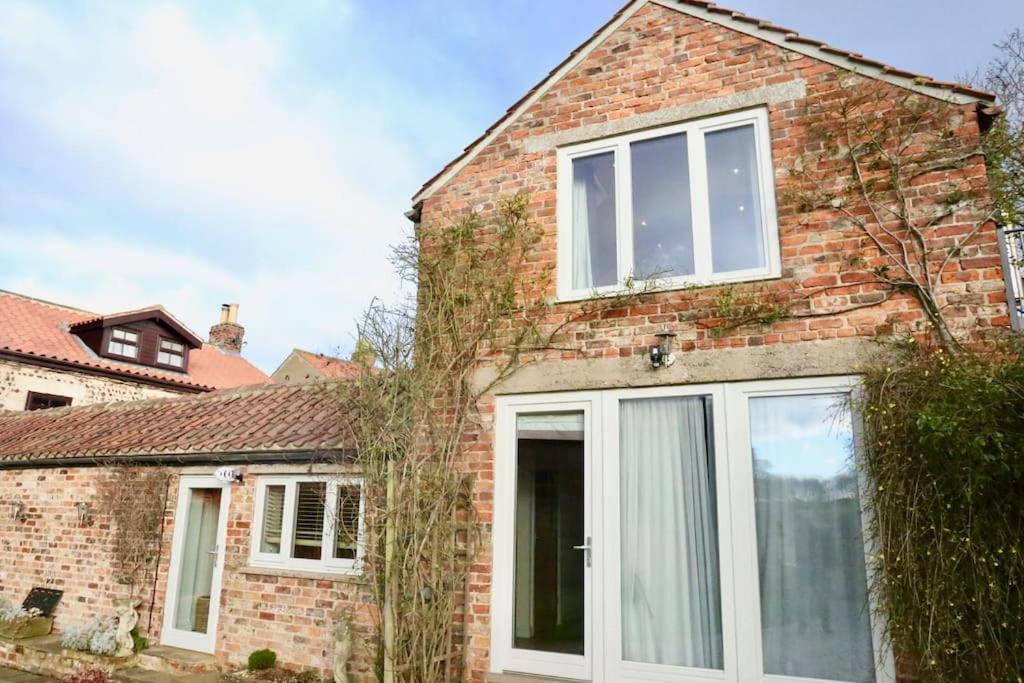 an extension to a brick house with sliding glass doors at Tanyard Barn - North Yorkshire in York