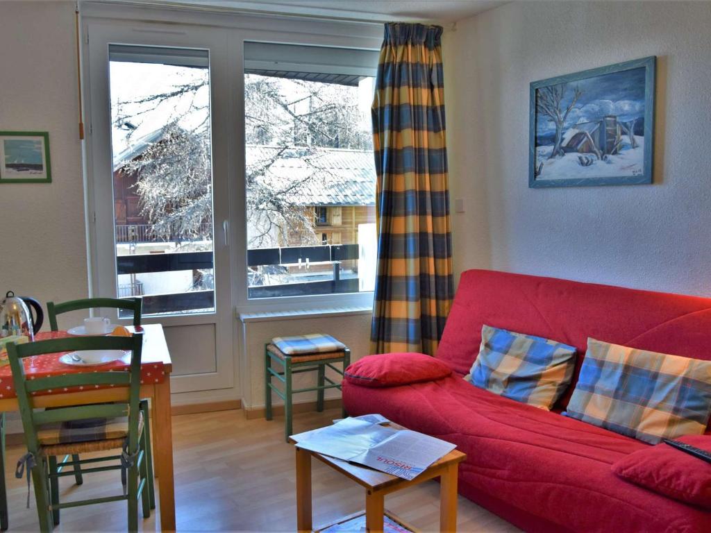 a living room with a red couch in front of a window at Appartement Risoul, 1 pièce, 4 personnes - FR-1-330-57 in Risoul