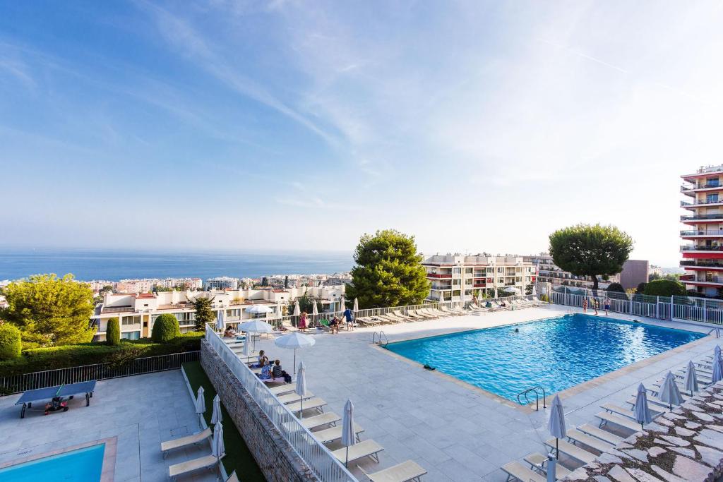 - une vue sur une piscine avec des chaises et un bâtiment dans l'établissement LE SIRIUS AP4314 By Riviera Holiday Homes, à Nice