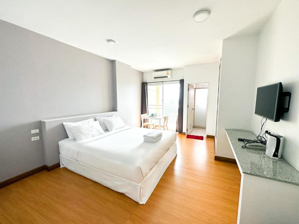 een hotelkamer met een wit bed en een televisie bij The Island Resort in Bangkok