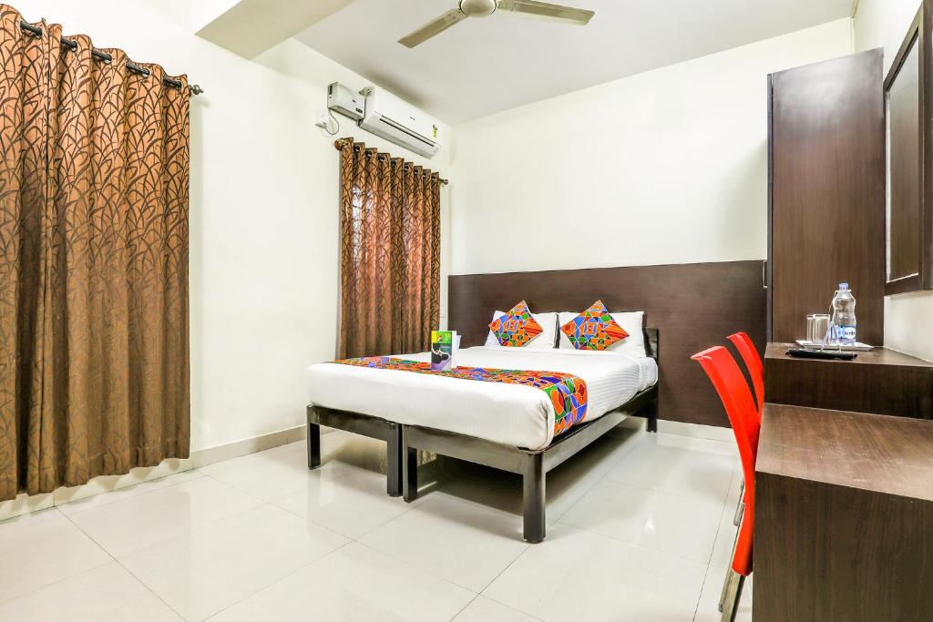 a bedroom with a bed and a orange chair at FabHotel RMS Comforts Yeshwantpur in Bangalore