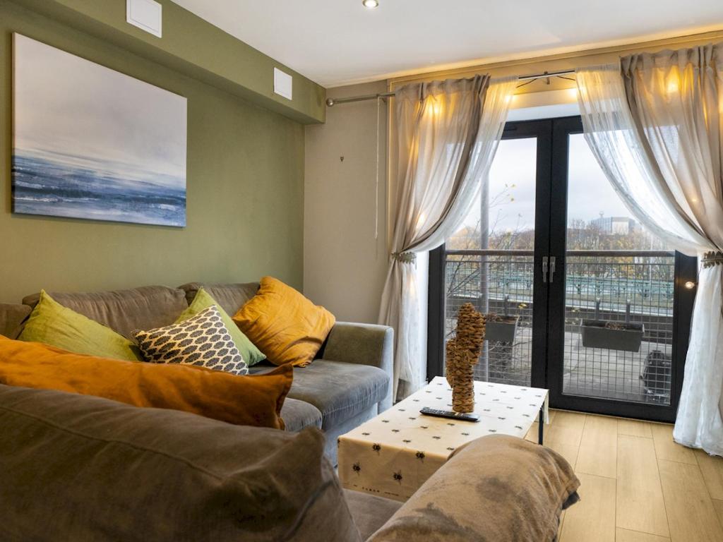 a living room with a couch and a large window at Pass the Keys Stunning 2BR Apt w Balcony Views City Centre in Belfast