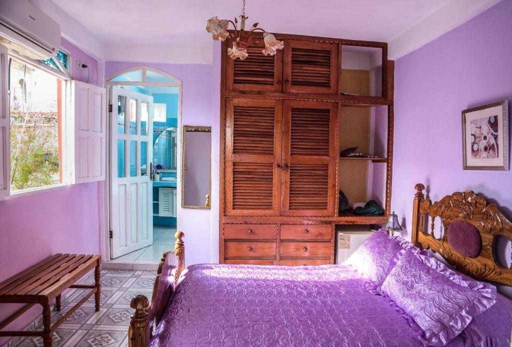 a bedroom with purple walls and a bed and a bench at Casa Mari y Santi Appartement 3 in Santiago de Cuba