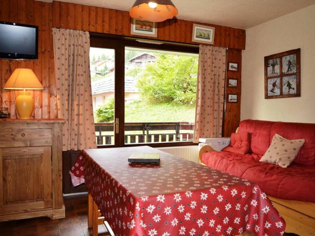 a living room with a red couch and a table at Appartement Le Grand-Bornand, 2 pièces, 6 personnes - FR-1-241-152 in Le Grand-Bornand