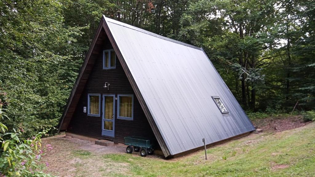 een klein zwart huis met een gambrel dak bij Ferienhaus Nr 16 am Twistesee in Bad Arolsen