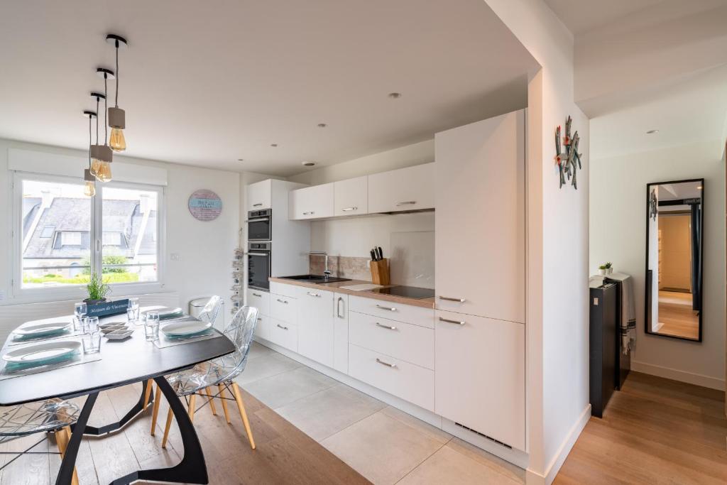 a kitchen with white cabinets and a dining table at Appartement vue mer a lIle Tudy in Île-Tudy