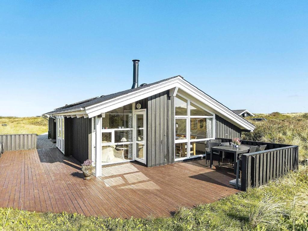 a house with a deck with a table on it at 8 person holiday home in Hj rring in Kærsgård Strand