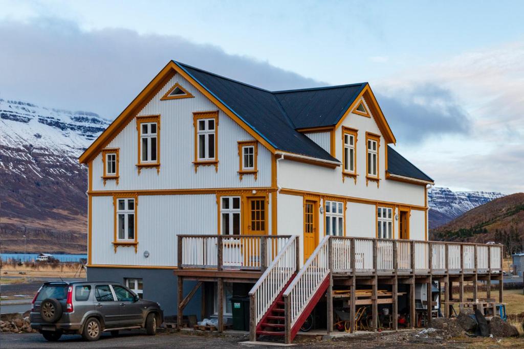 a house with a car parked in front of it at Steinholt, charming & just renovated apartment ! in Seyðisfjörður
