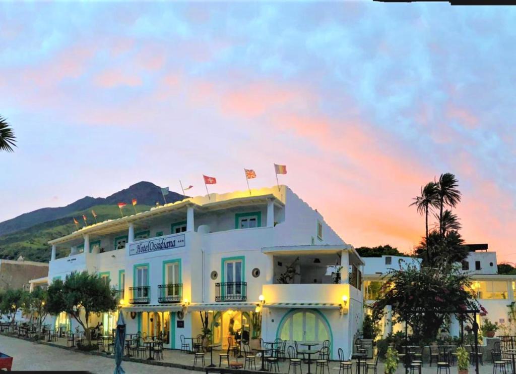 a large white building with palm trees at Hotel Ossidiana Stromboli in Stromboli