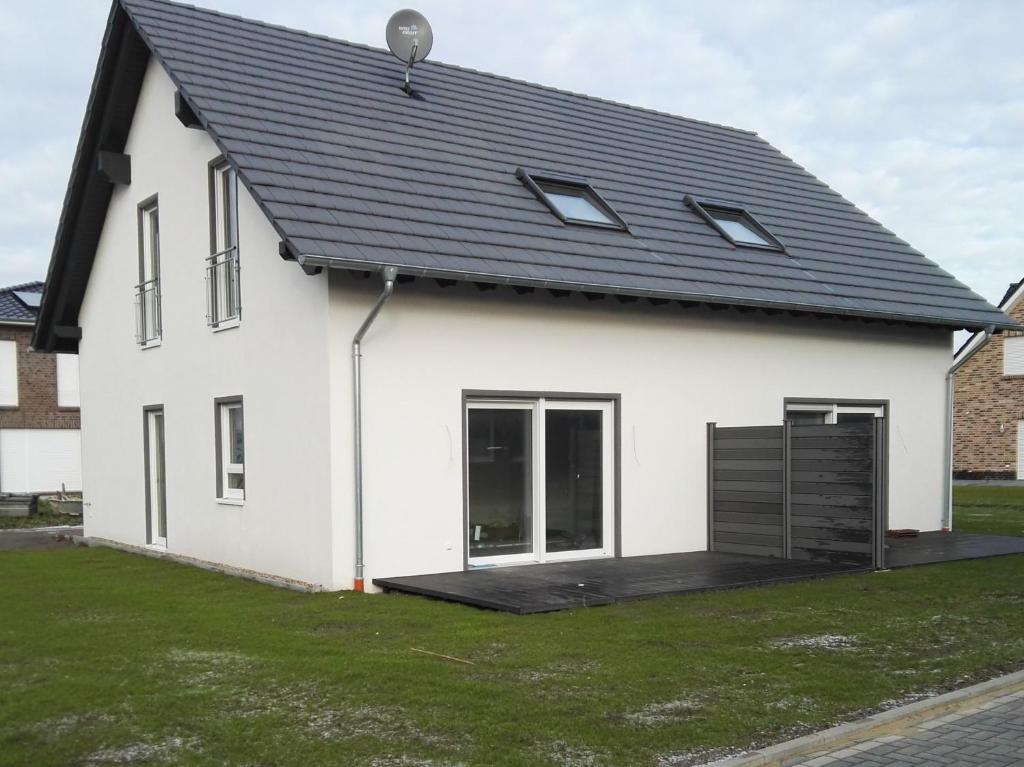 une maison blanche avec un toit noir dans l'établissement Haus Luv & Haus Lee - Nordseebad Burhave, à Burhave