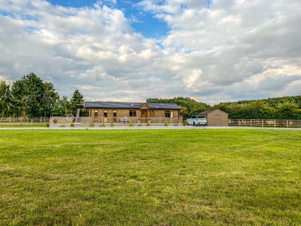 a large grassy field in front of a house at Immaculate 3-Bedroom Private Lodge near York in York