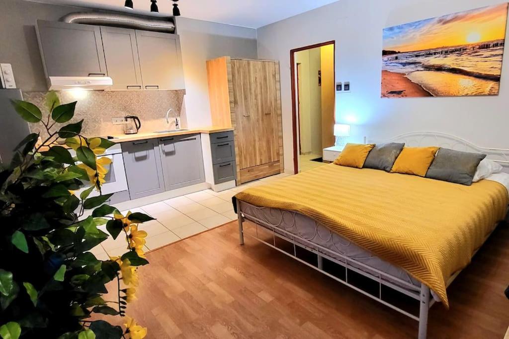 a bedroom with a bed with yellow sheets and a kitchen at Cozy modern Apartment SUNRISE studio 35m2 balcony 3 persons in Krakow
