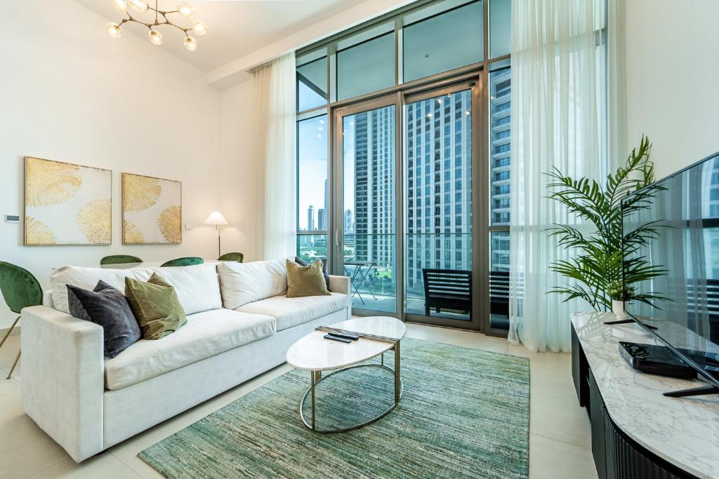 a living room with a white couch and a large window at Luxury StayCation - Fancy Apartment Connected To Burj Khalifa in Dubai