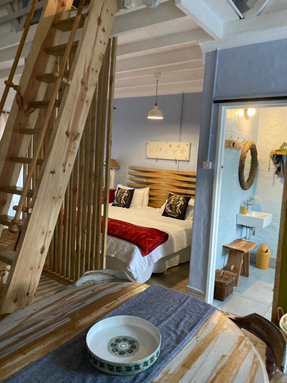 a bedroom with a bed and a staircase in a room at Bauhinia Beach Loft in Wilderness