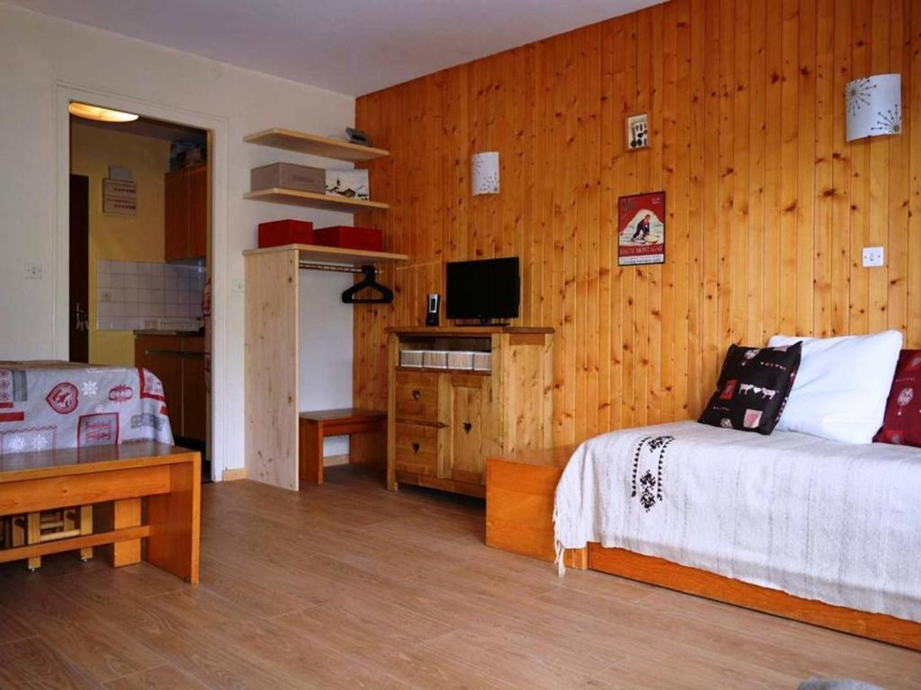 1 dormitorio con 1 cama y pared de madera en Appartement Le Grand-Bornand, 1 pièce, 4 personnes - FR-1-241-116, en Le Grand-Bornand