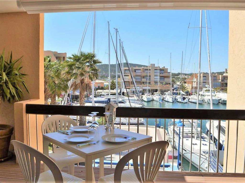 un balcon avec une table et des chaises et un port de plaisance dans l'établissement Appartement 3 pièces avec piscine et garage, proche plage - FR-1-251-6, à Bormes-les-Mimosas
