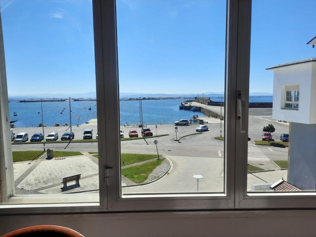 a window with a view of the ocean and a pier at Apartamentos Puerto de Aguiño in Couso