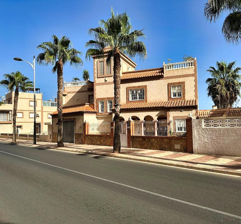 a building with palm trees on the side of a street at Lge 4 bed villa own pool 90 mts beach sea views in Roquetas de Mar