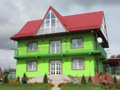 uma casa verde brilhante com um telhado vermelho em La Capra Vecinului em Oglinzi