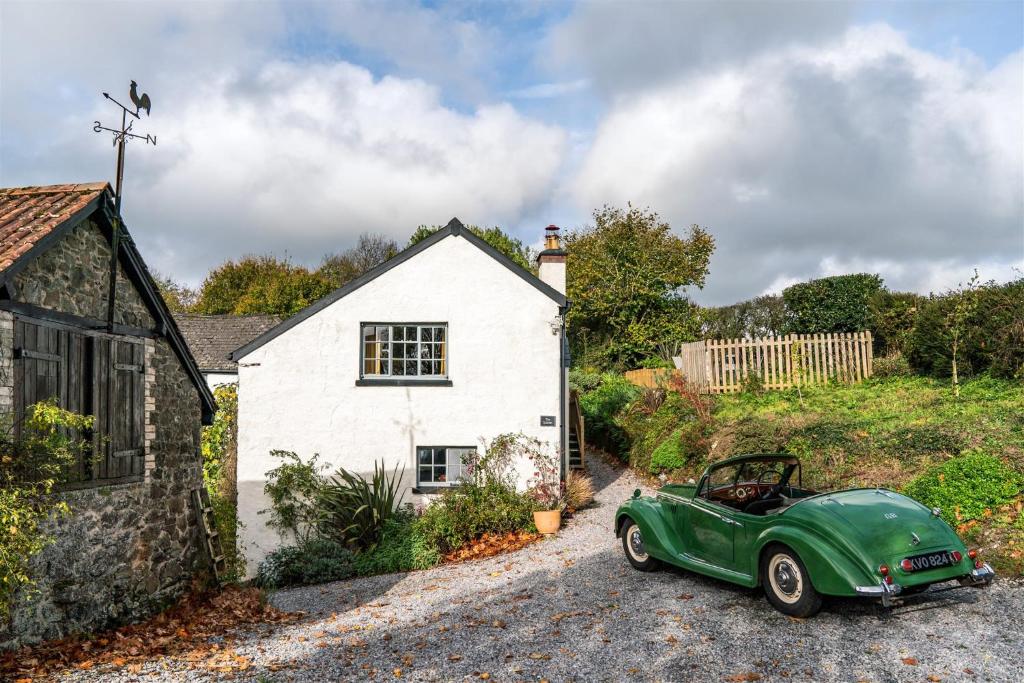 a green car parked in front of a white house at The Stables - Charming 15th-century rural bolthole in Newton Abbot