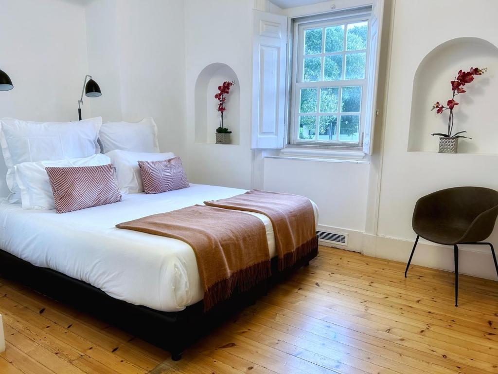 a bedroom with a bed with a chair and a window at Villa Vasco da Gama in Cascais