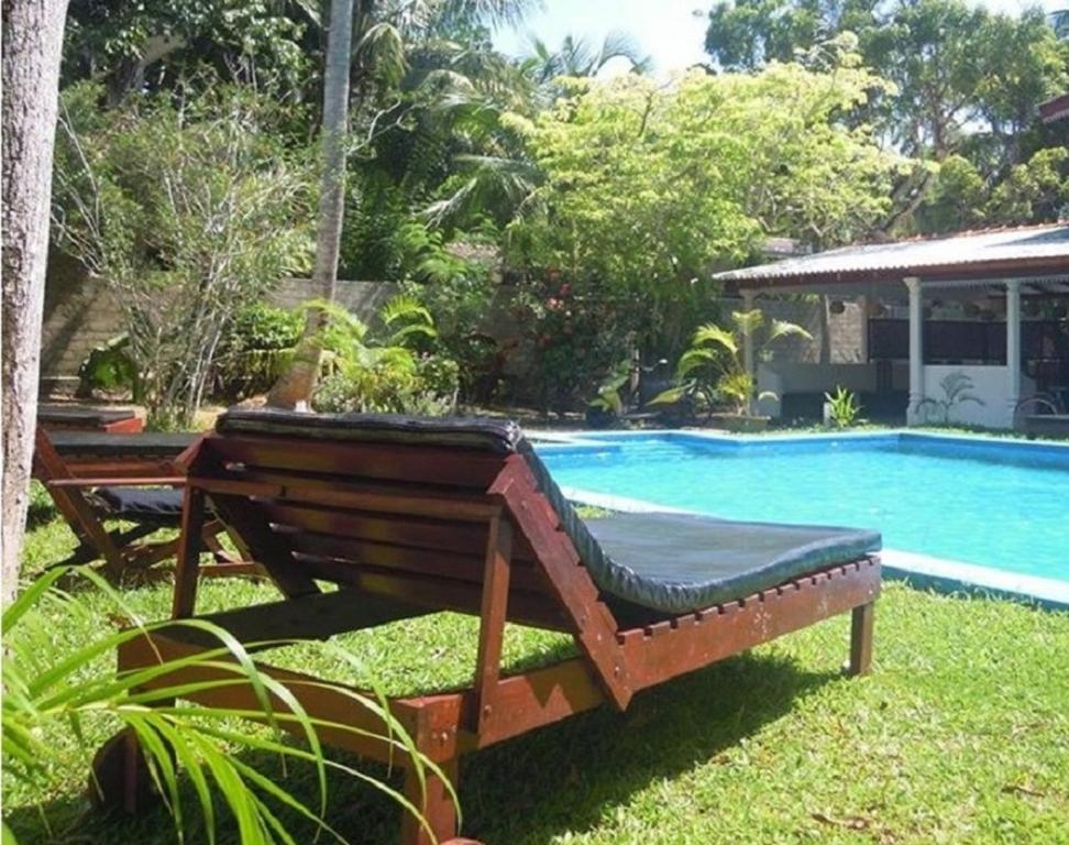 a wooden bench sitting next to a swimming pool at Villa Vidisa Hôtel Guest-House in Hikkaduwa