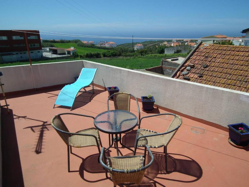 a patio with chairs and tables on a roof at West Terrace House - Ocean View in Lourinhã