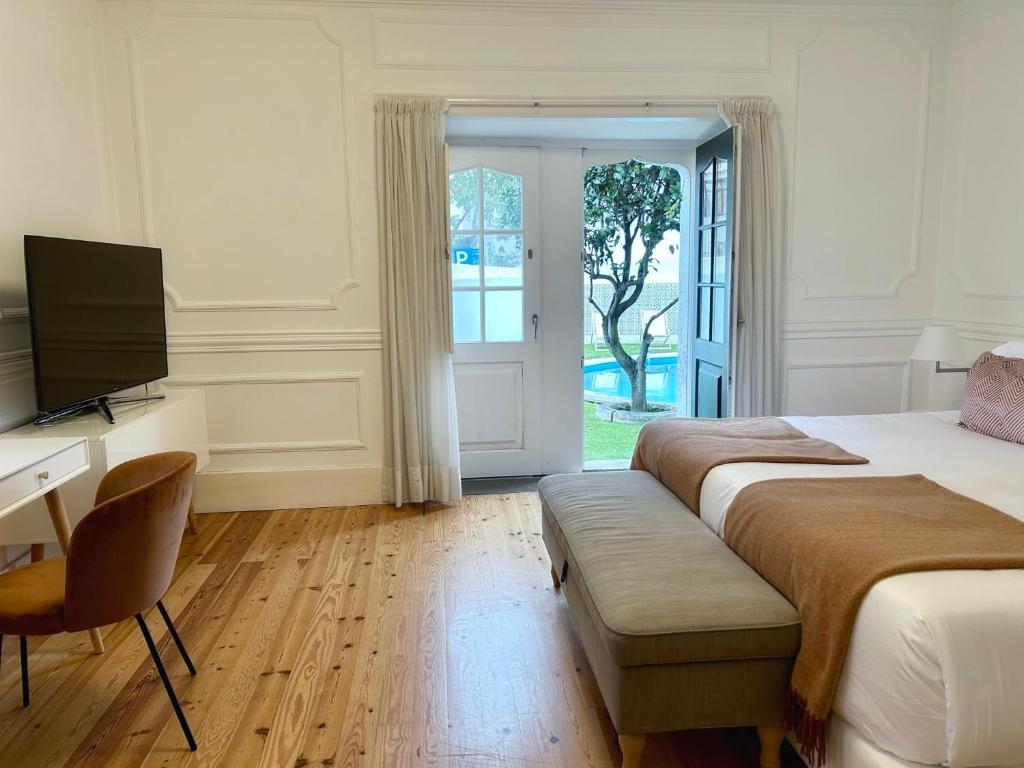 a bedroom with two beds and a desk and a television at Villa Vasco da Gama in Cascais