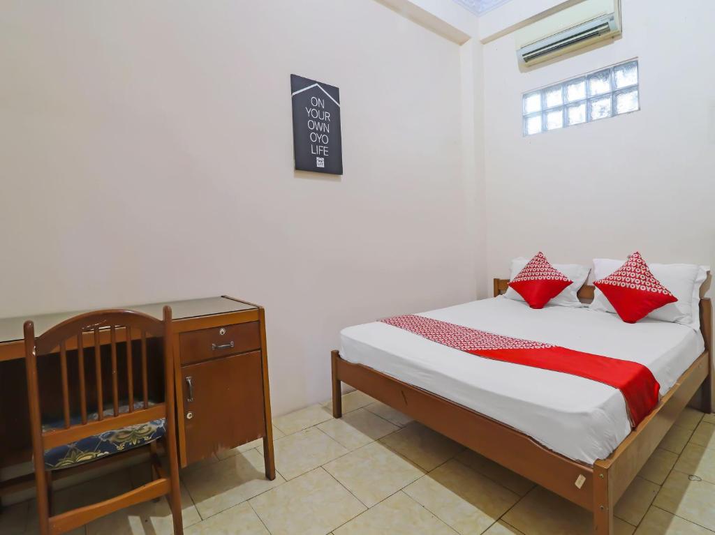 ein Schlafzimmer mit einem Bett mit roten Kissen und einem Kinderbett in der Unterkunft OYO 2899 Ardilia Bandara Syariah in Jambi