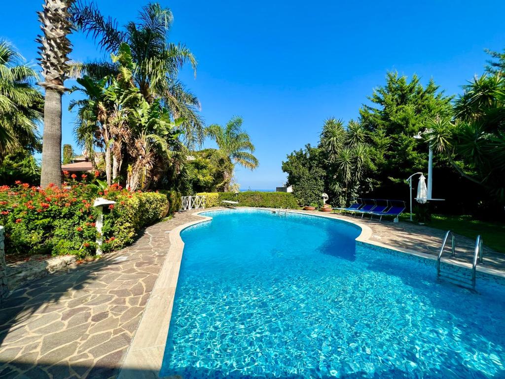 una piscina con agua azul y palmeras en Villa Talìa, en Carini